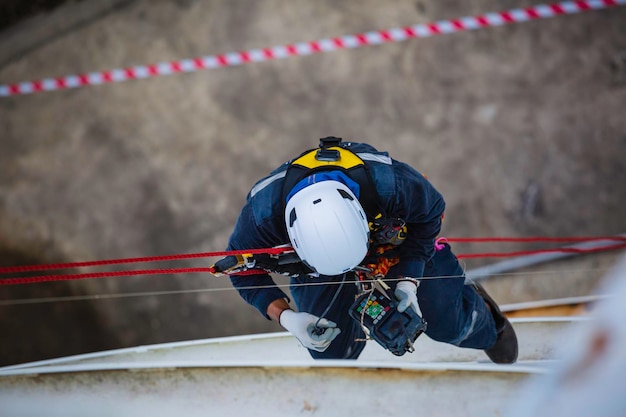 Top view male worker inspection wearing safety first harness rope safety line working at a high place on tank roof spherical