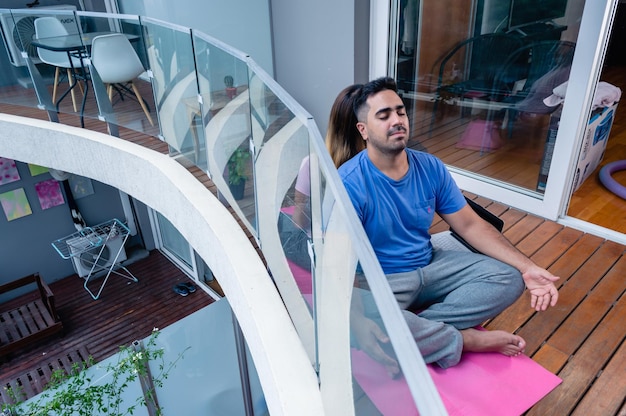 Top view man on apartment balcony meditating with his wife