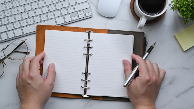 Top view man holding pen and empty notebook