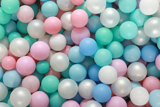 Top view of many pastel colourful gum balls in ball pool. They in playroom indoor playground for children party. Background and texture concept.