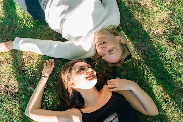 Top view of mature mother and daughter lay on the grass on sunny summer day