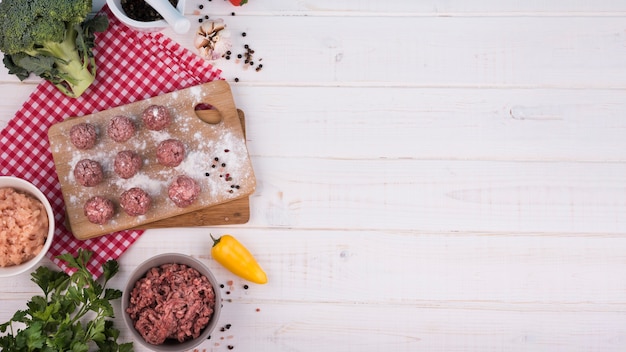 Top view meatballs on wooden board and minced meat with copy space