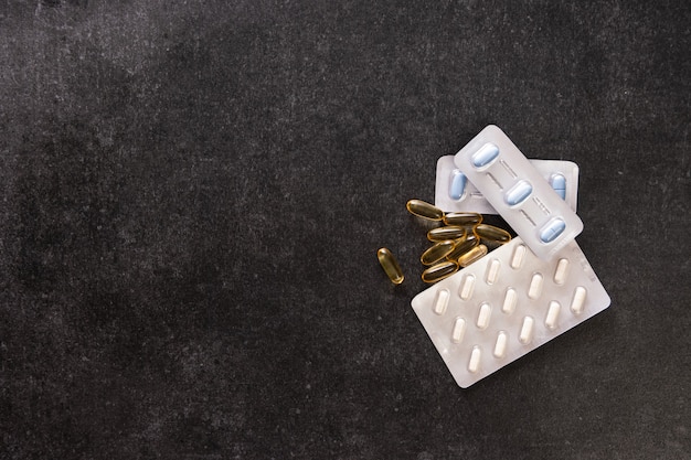 Top view of medical pills in packaging on a dark table with copy space