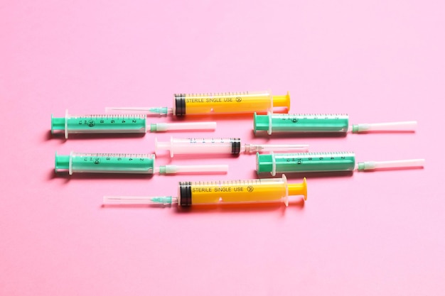 Top view of medical syringes with needles at pink background with copy space Injection treatment concept