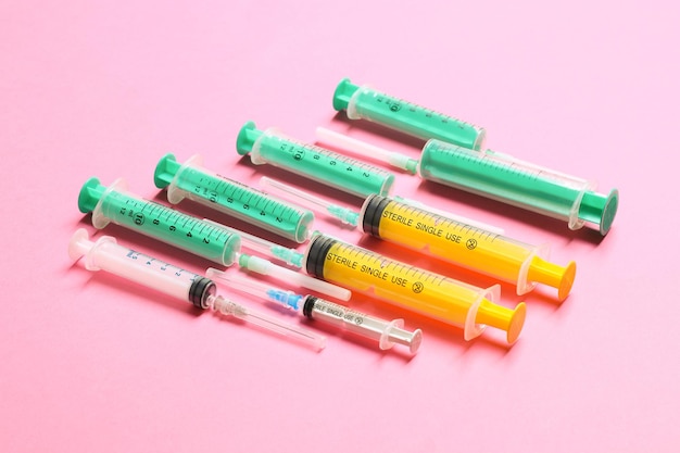 Top view of medical syringes with needles at pink background with copy space Injection treatment concept