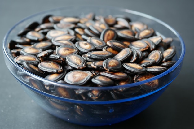 Top view of melon seeds in a bowl on black background