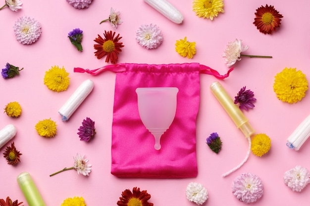 Top view on menstrual cup surrounded by flowers