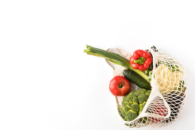 Top view of mesh shopping bag with organic eco vegetables isolated on white background. Caring for the environment and the rejection of plastic concept