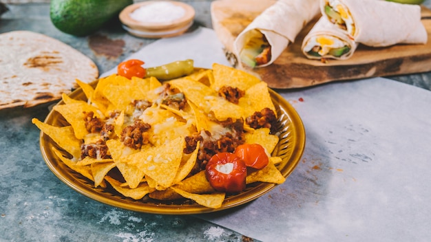 Top view of mexican nachos tortilla chips in bowl with mexican tacos on cutting board