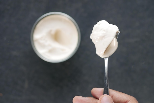 Top view of milk cream on a silver spoon and container on background