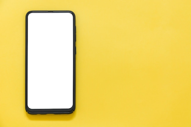 Top view of mockup black color smartphone with a blank desktop on yellow background