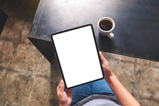 Top view mockup image of a woman holding digital tablet with blank white desktop screen in cafe