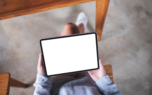 Top view mockup image of a woman holding digital tablet with blank white desktop screen