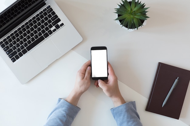 Top view of mockup of mobile phone with white copy space screen, flat lay, female workspace concept for woman office desk