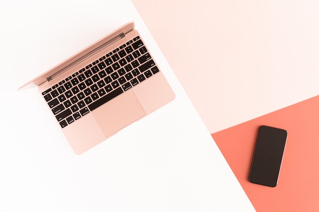 Top view of modern pink gold air laptop and mobile phone on pastel