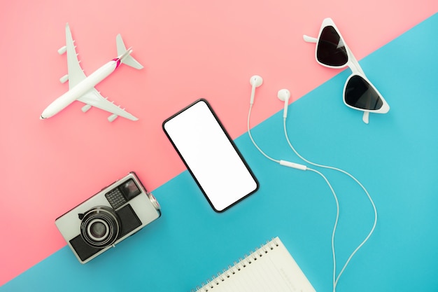 Top view modern smartphone, hat with camera on pink and blue color background. Summer holiday and travel concept.