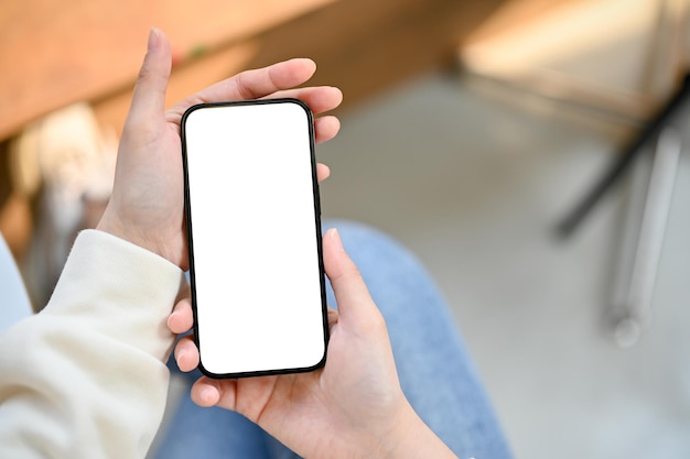 Top view of a modern smartphone mockup is in a woman's hands over blurred background