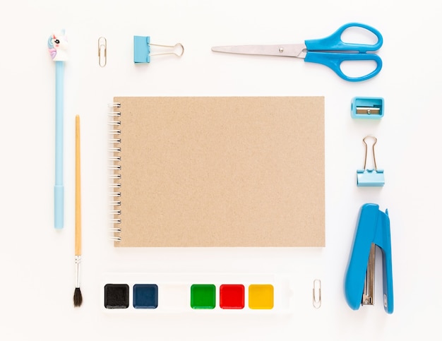 Top view of modern white blue office desktop with school supplies and stationery on table around empty space for text. Back to school concept flat lay with mockup