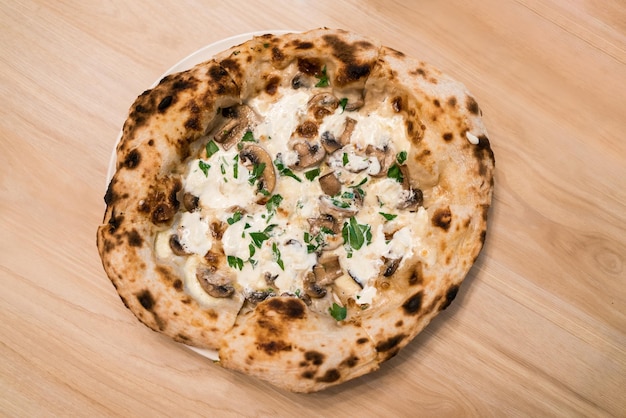 Top view of Neapolitan pizza Stirfried Swiss mushrooms topped with special truffle sauce pizza Served on a white plate on a wooden table Italian fresh baked Napoli pizza