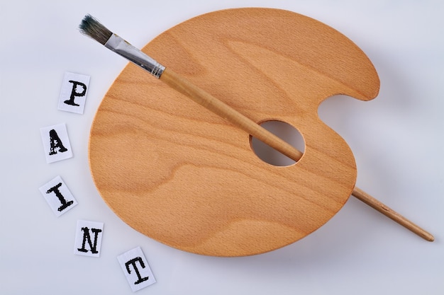 Top view new wooden palette with paintbrush isolated on white background