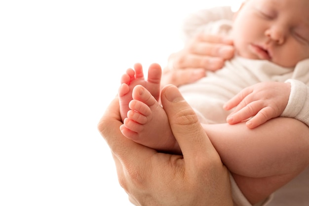 Top view of a newborn girl lying in a white overalls in the arms of her parents Beautiful portrait of a little girl with closed eyes The hands of the parents gently hug the child39s body