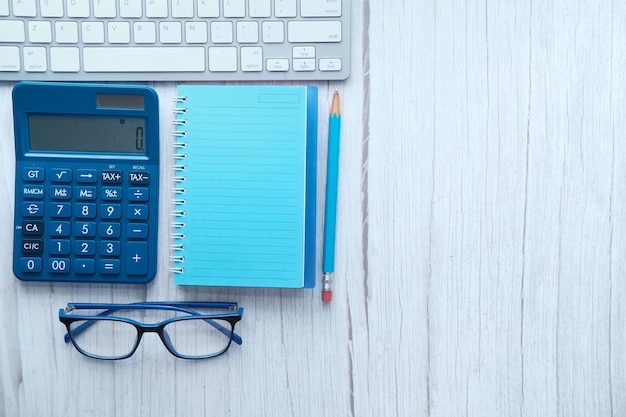 Top view of note pad, calculator, pen on white background.