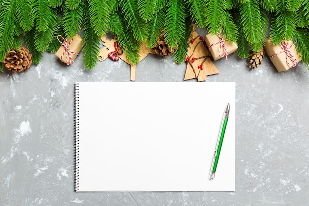 Top view of a notebook on cement background made of fir tree and Christmas decorations