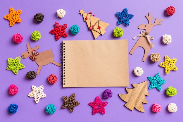 Top view of notebook. New Year decorations on purple background. Festive stars and balls. Merry Christmas concept.