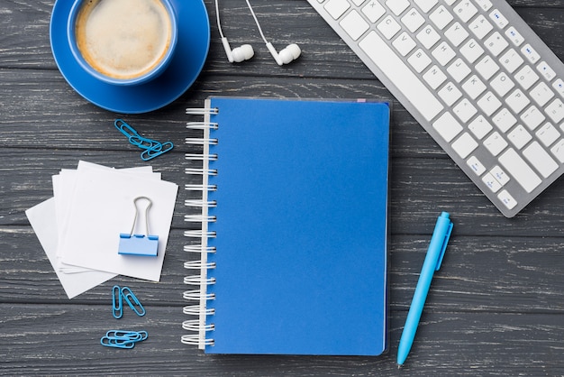 Top view of notebook on wooden desk with sticky notes and coffee cup