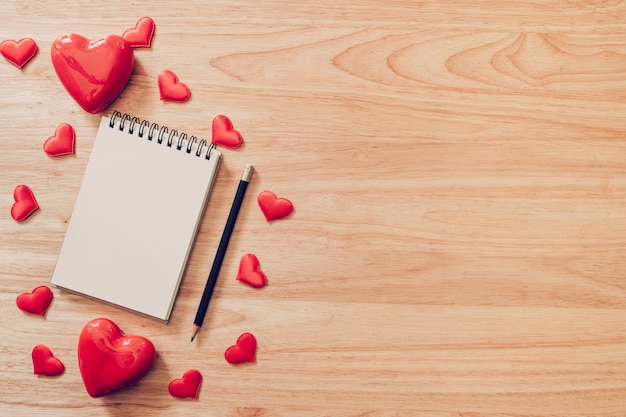 Top view notepad and red heart on wood background for valentine day with copy space.