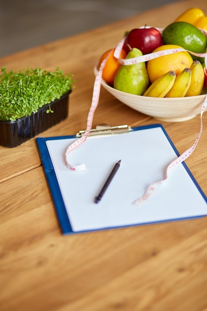 Top view of Nutritionist, dietitian workplace with measuring tape and bowl with healthy vegetables and fruits