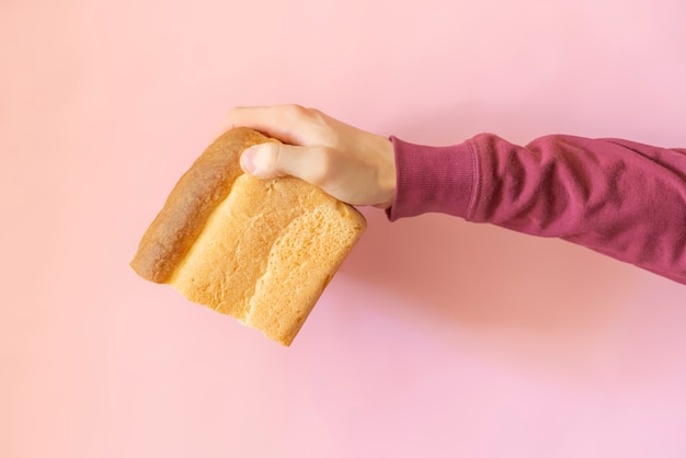 Top view o person's hand holding a loa bread  over the color background