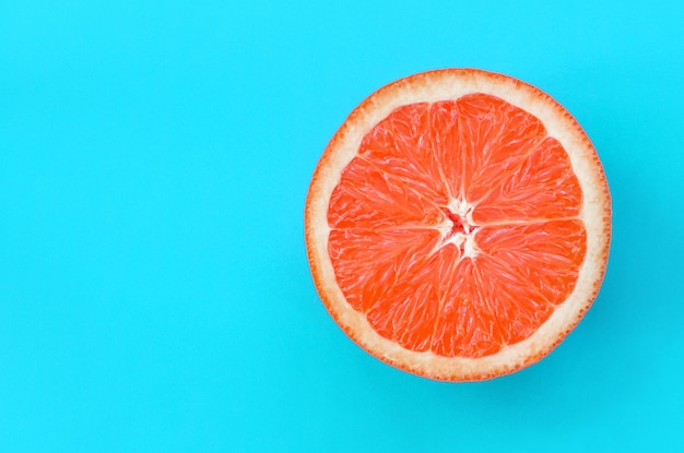 Top view of an one grapefruit slice on bright blue color