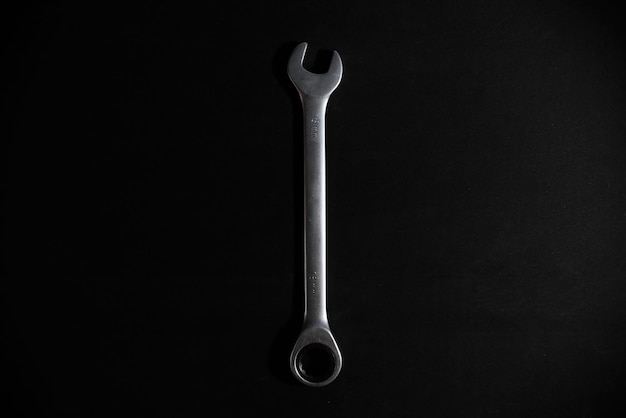 Top view one steel combination wrench on black background