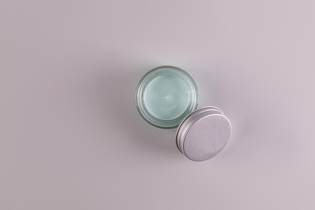 Top view of an open jar of a cosmetic product with a delicate blue texture for everyday face and body skin care spa massage Gray background