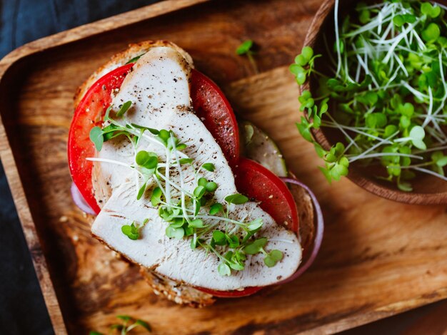 Top view of open sandwich with sliced turkey meat and fresh vegetables in a wooden tray Healthy eating concept