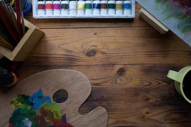 Top view paint brushes watercolors palette and coffee cup on wooden table