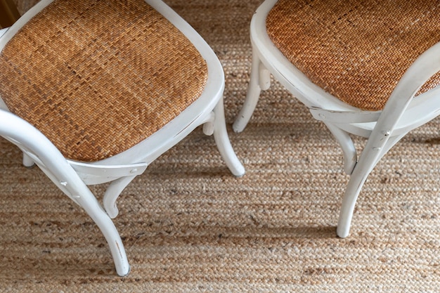 Top view of pair of white retro style chairs with metal wooden frame and wicker seat on seat