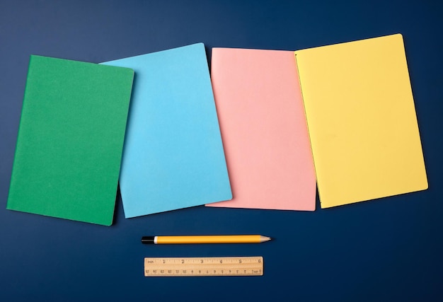 Top view pastel notebook with pencil and stationery on navy blue table background