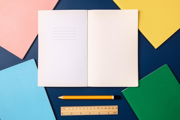 Top view pastel notebook with pencil and stationery on navy blue table background