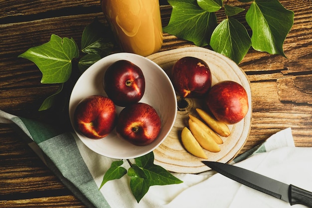 Top view of peaches whole and sliced on a wooden surface surrounded by leaves