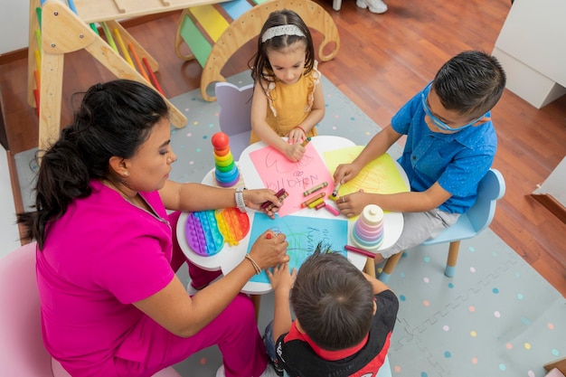 Top view of a pediatrician doctor drawing with 3 children at a table in her office