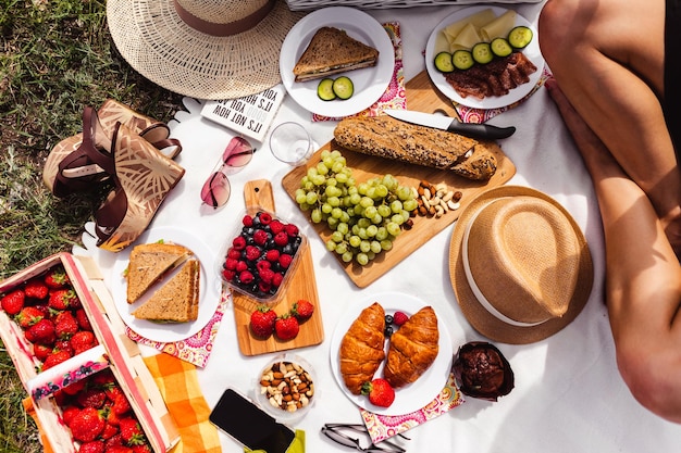 Top view people take food from checkered picnic blanket. Outdoor summer family picnic.