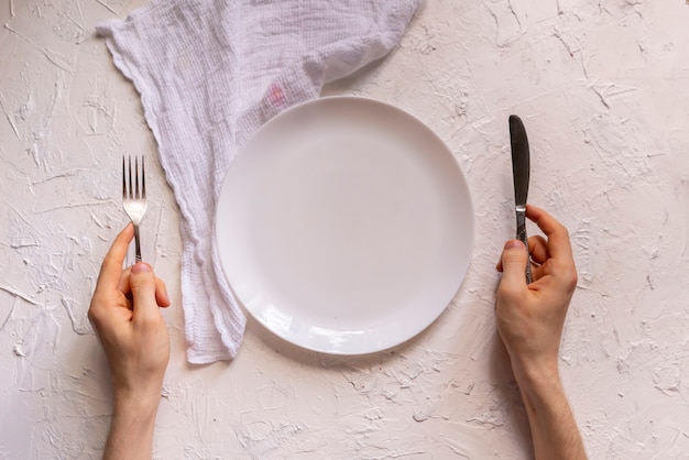 Top view of person's hands on the table with empty plate