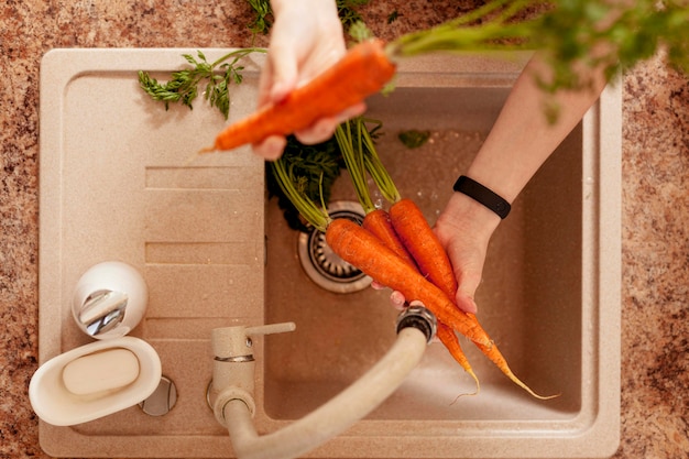 Top view of person washing carrots in preparation for dinner