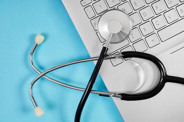 Top view of Phonendoscope or stethoscope on laptop keyboard on blue background