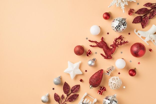 Top view photo of composition white silver red christmas decorations snowflakes stars disco balls cone deer ice skates sleigh sprigs confetti serpentine on isolated beige background with empty space