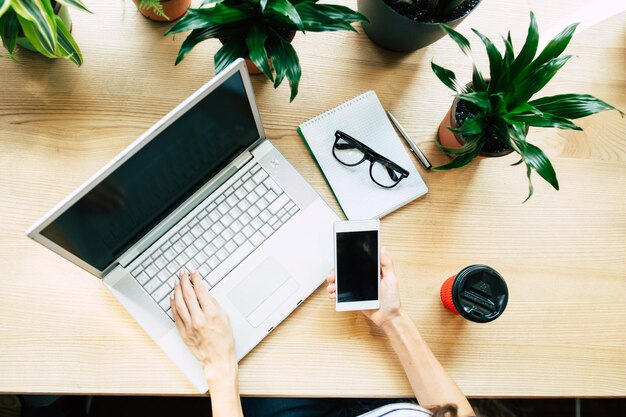 Top view photo of Digital laptop, smartphone and cup of coffee on wooden table in cafe or office