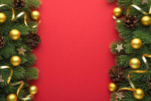 Top view photo of golden christmas tree balls pine cones glowing stars and gold serpentine on pine branches on isolated red background with blank space