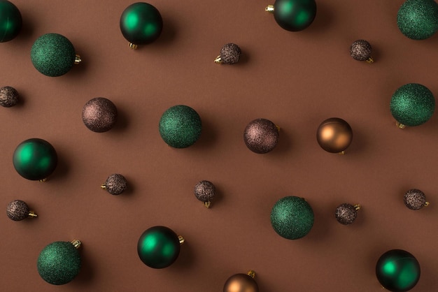 Top view photo of green brown and golden christmas tree balls on isolated brown background